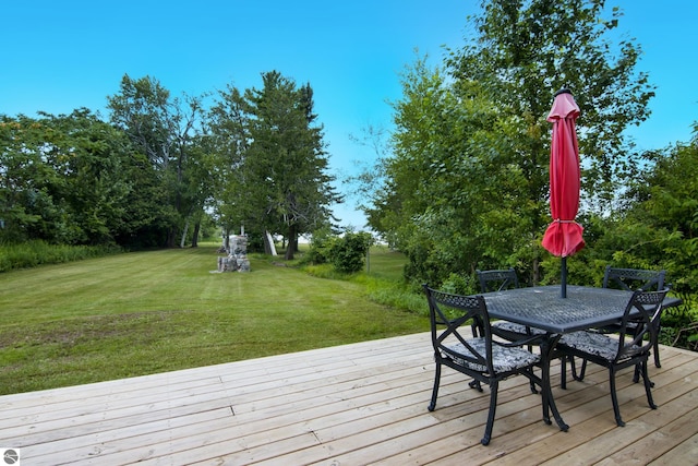 8489 S Glen Lake Rd, Glen Arbor, MI 49636 - wooden terrace featuring a lawn, outdoor dining area, and view of scattered trees