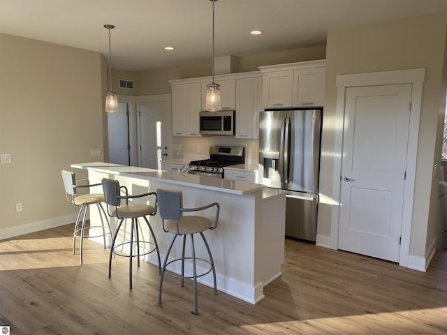 7559 E Meadows Dr Unit 52, Traverse City, MI 49621 - kitchen featuring stainless steel appliances, wood finished floors, a kitchen island, white cabinets, and recessed lighting