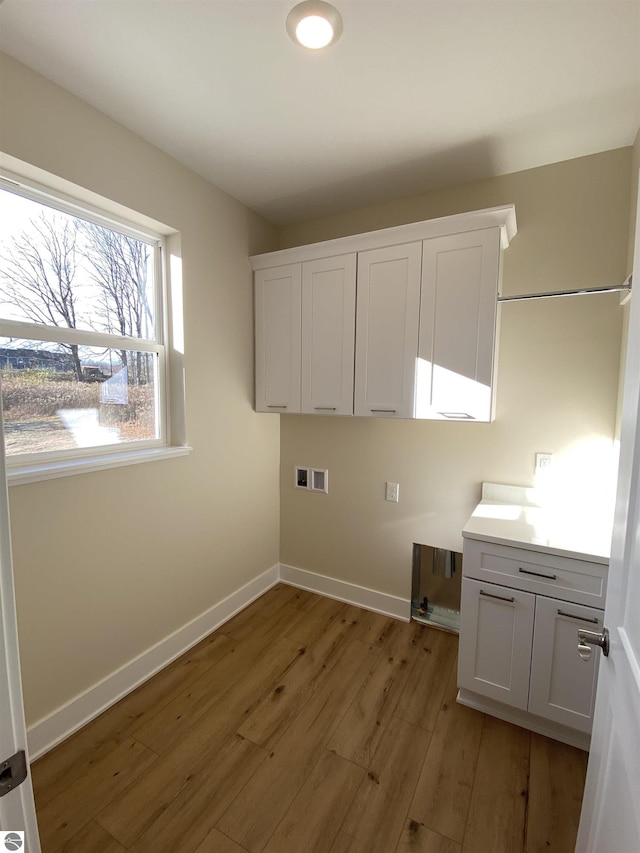 7559 E Meadows Dr Unit 52, Traverse City, MI 49621 - laundry room featuring cabinet space, light wood finished floors, washer hookup, and baseboards