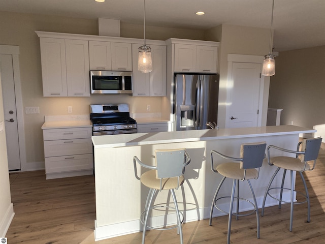 7559 E Meadows Dr Unit 52, Traverse City, MI 49621 - kitchen with stainless steel appliances, light wood-type flooring, a center island with sink, light countertops, and baseboards