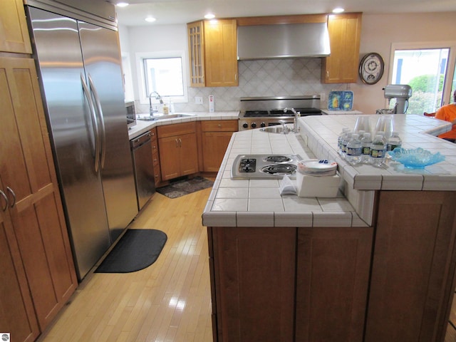 2011 Douglas Dr, Tawas City, MI 48763 - kitchen with extractor fan, stainless steel appliances, tile counters, a sink, and a kitchen island with sink