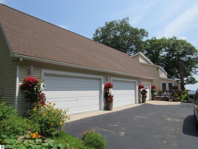 2011 Douglas Dr, Tawas City, MI 48763 - view of side of home featuring roof with shingles, asphalt driveway, and a garage
