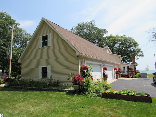 2011 Douglas Dr, Tawas City, MI 48763 - view of side of property with a garage, driveway, a lawn, and a shingled roof