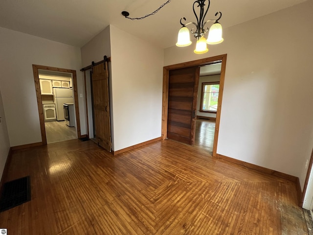 506 E Division St, Cadillac, MI 49601 - unfurnished room featuring baseboards, a barn door, a chandelier, and wood finished floors