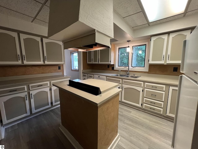 506 E Division St, Cadillac, MI 49601 - kitchen featuring a drop ceiling, a sink, freestanding refrigerator, wood finished floors, and a kitchen island