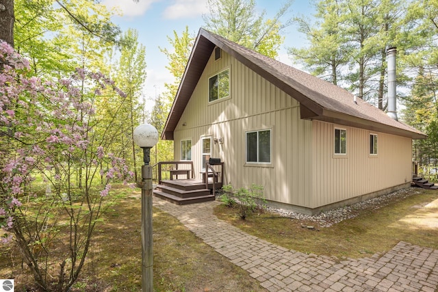 3228 S Skeba Rd S, Lake Leelanau, MI 49653 - view of side of home featuring a shingled roof, a deck, and board and batten siding