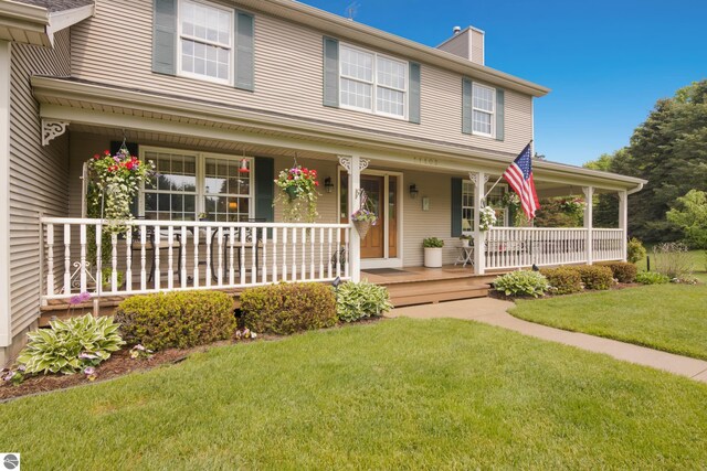 11103 S Ramblewood Dr, Cedar, MI 49621 - view of front of home featuring covered porch, a chimney, and a front lawn