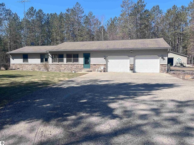 2168 S Lorenz Rd, Tawas City, MI 48763 - view of front facade featuring stone siding, a garage, concrete driveway, and a front lawn