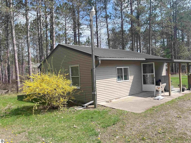 2168 S Lorenz Rd, Tawas City, MI 48763 - back of property featuring metal roof, a patio area, and a lawn