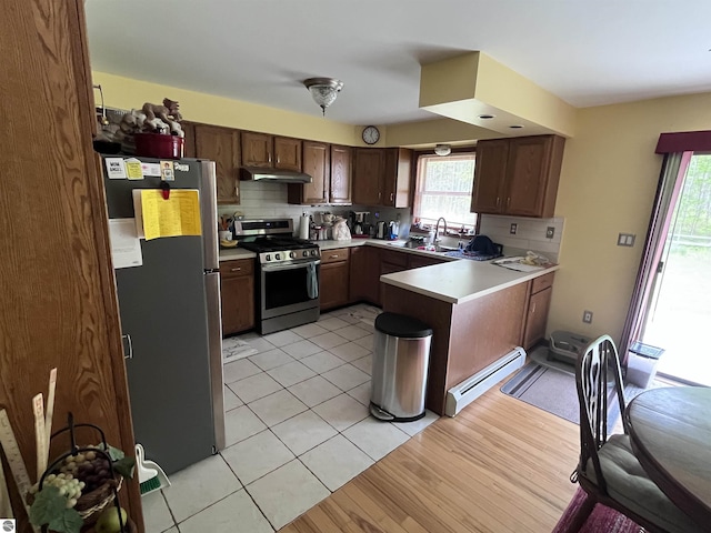 2168 S Lorenz Rd, Tawas City, MI 48763 - kitchen with appliances with stainless steel finishes, under cabinet range hood, a baseboard radiator, a peninsula, and tasteful backsplash