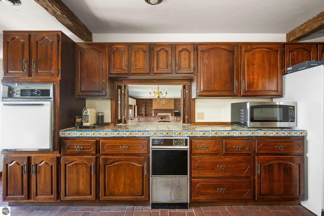 12150 N Seven Pines Rd, Northport, MI 49670 - kitchen featuring oven, brick patterned flooring, stainless steel microwave, beamed ceiling, and tile countertops
