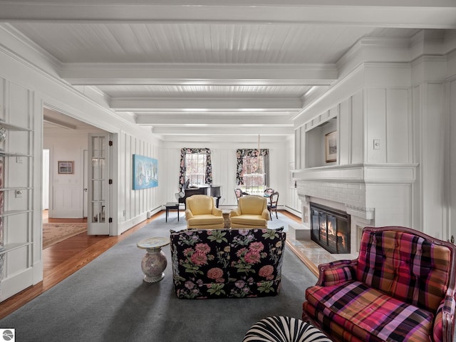 431 Michigan Ave, Charlevoix, MI 49720 - living area with a decorative wall, beamed ceiling, a fireplace, wood finished floors, and crown molding