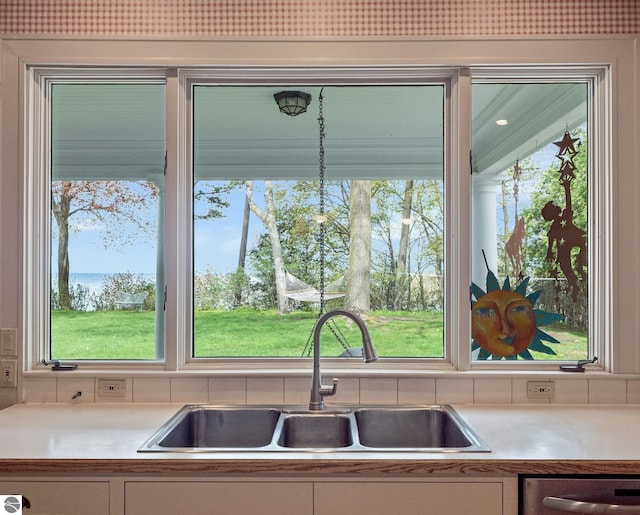 431 Michigan Ave, Charlevoix, MI 49720 - kitchen featuring a sink, light countertops, dishwashing machine, backsplash, and white cabinetry