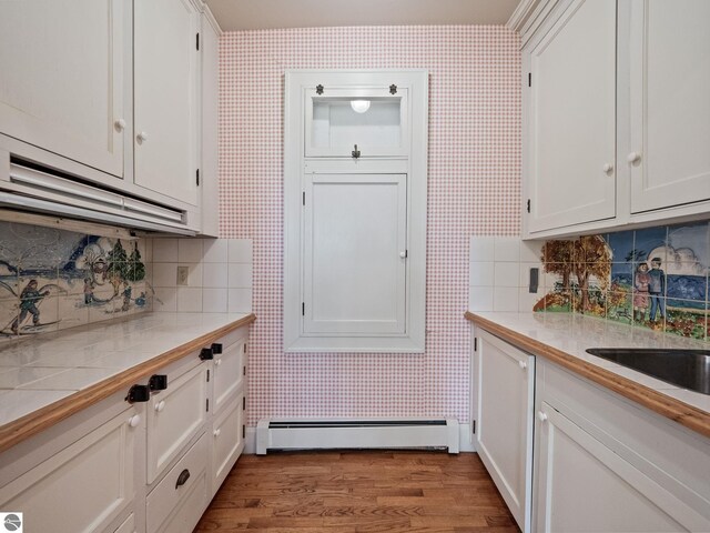 431 Michigan Ave, Charlevoix, MI 49720 - kitchen with a baseboard radiator, wallpapered walls, white cabinetry, and light wood-style floors