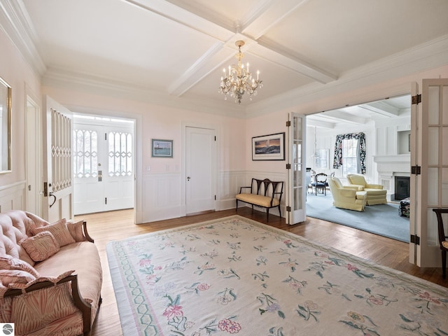 431 Michigan Ave, Charlevoix, MI 49720 - foyer with light wood-style floors, a chandelier, beam ceiling, crown molding, and a decorative wall