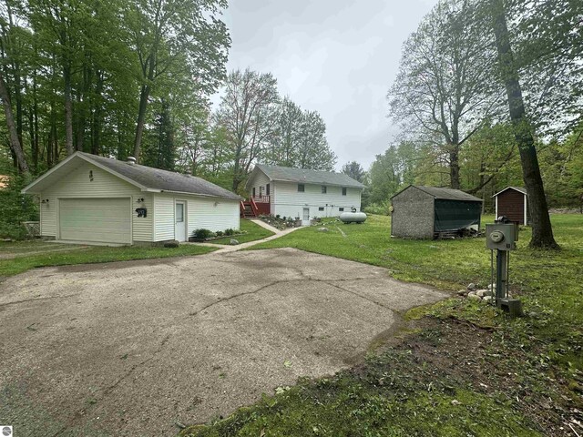 142 Forest Trl, Leroy, MI 49655 - view of side of home featuring an outdoor structure, a detached garage, a lawn, and view of wooded area