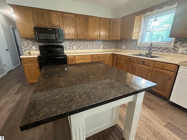 142 Forest Trl, Leroy, MI 49655 - kitchen with black appliances, a sink, wood finished floors, and decorative backsplash
