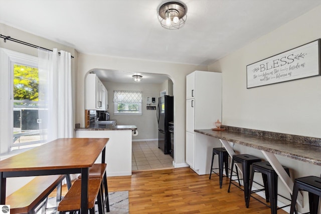 140 S State St, Alma, MI 48801 - dining area with arched walkways, healthy amount of natural light, light wood-style floors, and baseboards