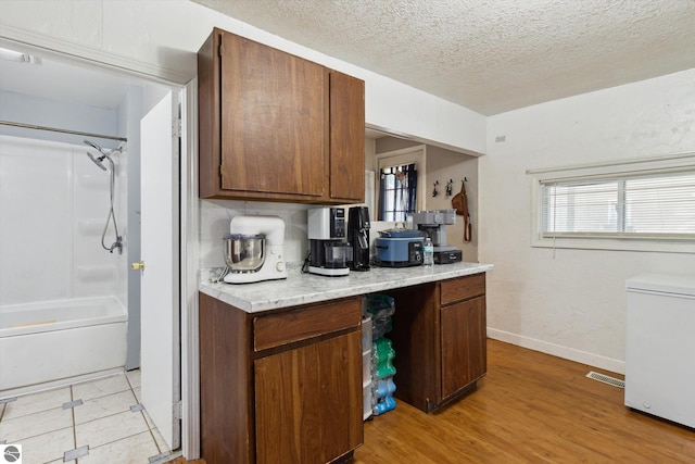 618 N River Ave, Alma, MI 48801 - kitchen with fridge, light countertops, plenty of natural light, light wood-style flooring, and a textured ceiling
