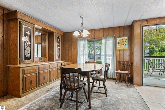 14501 Williams Dr, Elk Rapids, MI 49629 - dining area with healthy amount of natural light, wooden walls, a chandelier, a textured ceiling, and light tile patterned flooring
