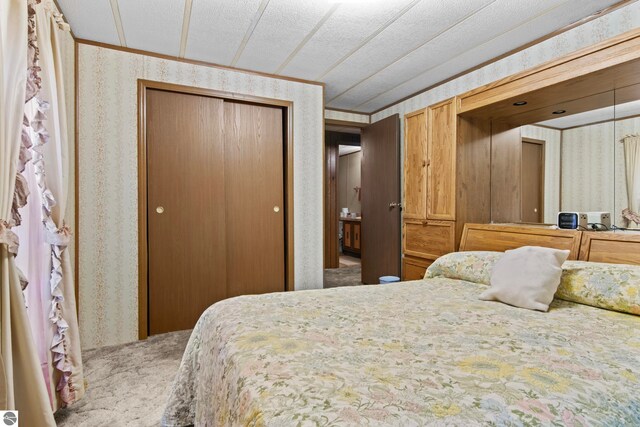 14501 Williams Dr, Elk Rapids, MI 49629 - bedroom featuring wallpapered walls, a closet, and crown molding