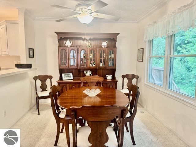 705 Eastgate Pl Unit 10 B, Traverse City, MI 49686 - dining area featuring light carpet, a ceiling fan, ornamental molding, and baseboards