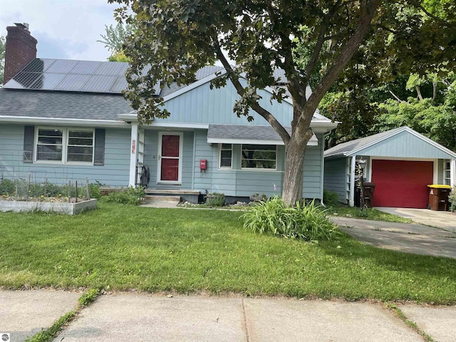 906 Vassar St, Alma, MI 48801 - ranch-style home featuring roof with shingles, a front yard, roof mounted solar panels, a chimney, and a garage