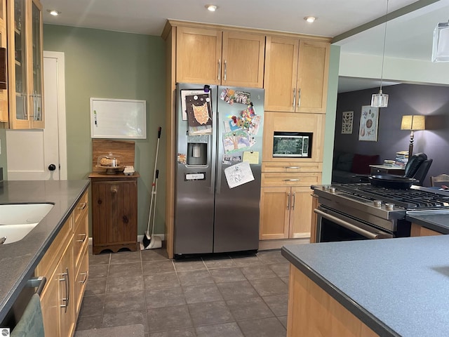 906 Vassar St, Alma, MI 48801 - kitchen featuring stainless steel appliances, light brown cabinetry, dark countertops, glass insert cabinets, and hanging light fixtures