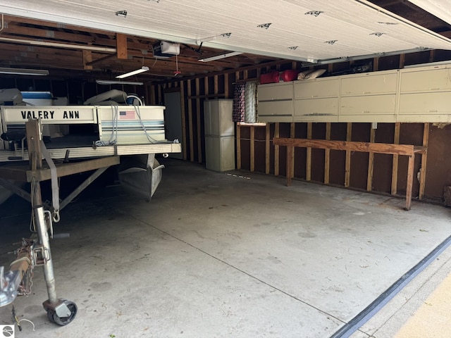 11748 NE Franklin St, Kalkaska, MI 49646 - garage featuring freestanding refrigerator and a garage door opener
