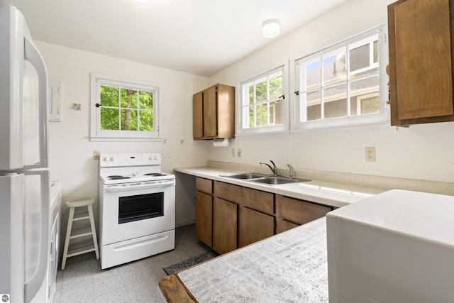 1884 Beech Rd, Frankfort, MI 49635 - kitchen featuring white electric range, freestanding refrigerator, a sink, brown cabinets, and light countertops
