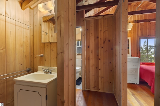 1884 Beech Rd, Frankfort, MI 49635 - bathroom with wood walls, vanity, hardwood / wood-style flooring, toilet, and beamed ceiling