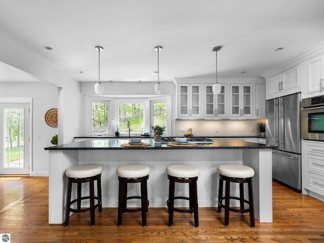 107 Hillcrest Ct, Traverse City, MI 49684 - kitchen featuring appliances with stainless steel finishes, white cabinetry, a kitchen island, a kitchen breakfast bar, and recessed lighting