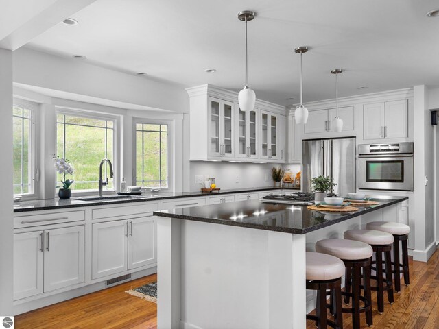 107 Hillcrest Ct, Traverse City, MI 49684 - kitchen with appliances with stainless steel finishes, a sink, white cabinets, a center island, and light wood-type flooring
