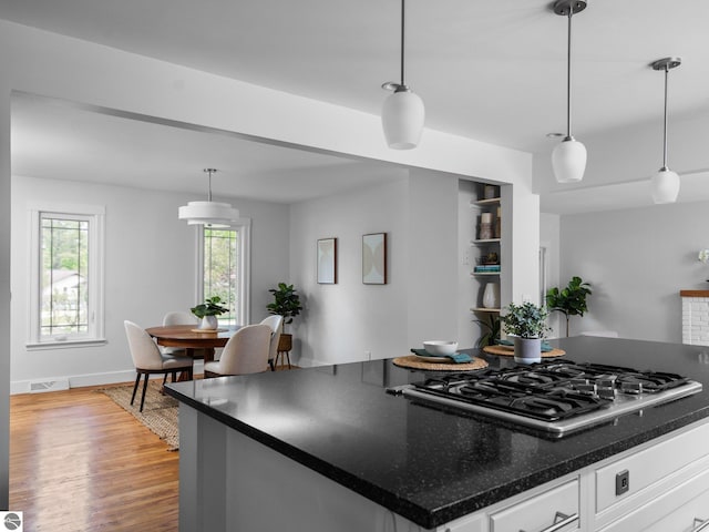 107 Hillcrest Ct, Traverse City, MI 49684 - kitchen with stainless steel gas cooktop, light wood-style flooring, white cabinetry, and pendant lighting