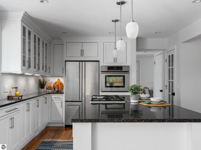 107 Hillcrest Ct, Traverse City, MI 49684 - kitchen featuring appliances with stainless steel finishes, dark wood-style flooring, glass insert cabinets, a center island, and dark stone countertops