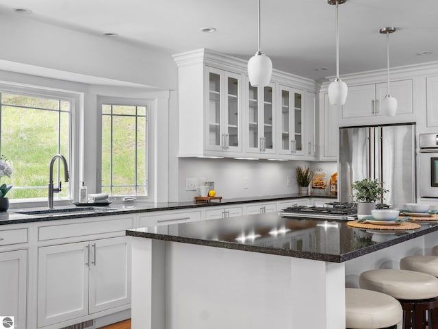 107 Hillcrest Ct, Traverse City, MI 49684 - kitchen with a sink, appliances with stainless steel finishes, white cabinets, glass insert cabinets, and a center island