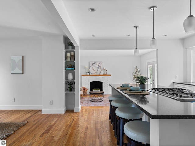 107 Hillcrest Ct, Traverse City, MI 49684 - kitchen with dark countertops, stainless steel gas stovetop, light wood-style flooring, a brick fireplace, and recessed lighting