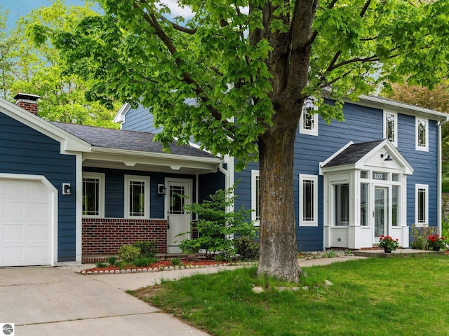 107 Hillcrest Ct, Traverse City, MI 49684 - view of front of home featuring a garage, brick siding, a front yard, a chimney, and concrete driveway
