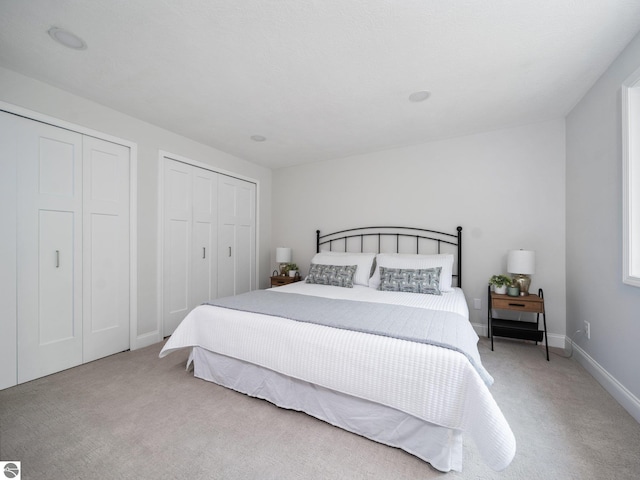 107 Hillcrest Ct, Traverse City, MI 49684 - bedroom featuring light carpet, two closets, and baseboards