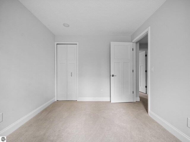 107 Hillcrest Ct, Traverse City, MI 49684 - unfurnished bedroom featuring light carpet, baseboards, and a closet