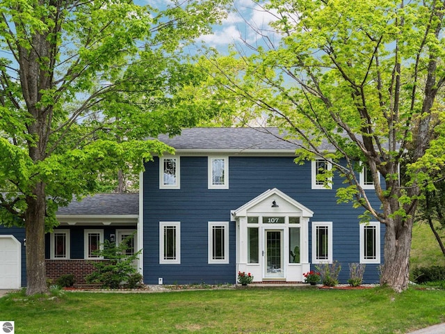 107 Hillcrest Ct, Traverse City, MI 49684 - colonial-style house with a front lawn, an attached garage, and a shingled roof