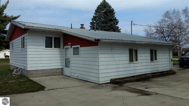 205 Fannie St, Au Gres, MI 48703 - view of side of property featuring metal roof, a chimney, and a patio