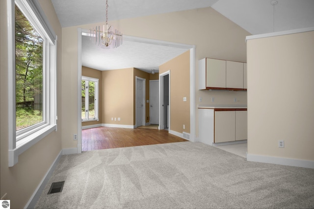 1631 Melody Ln, Interlochen, MI 49643 - empty room featuring light colored carpet, a chandelier, lofted ceiling, and baseboards