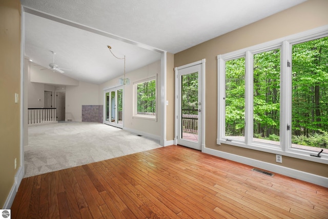 1631 Melody Ln, Interlochen, MI 49643 - unfurnished living room featuring a ceiling fan, baseboards, wood-type flooring, and vaulted ceiling