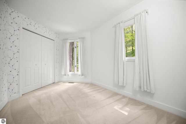 1631 Melody Ln, Interlochen, MI 49643 - unfurnished bedroom featuring baseboards, carpet floors, a closet, and wallpapered walls