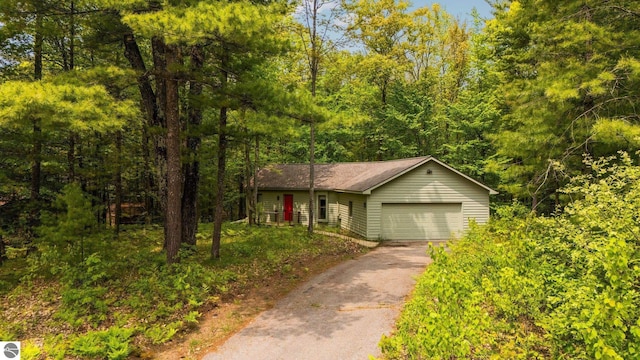 1631 Melody Ln, Interlochen, MI 49643 - view of front facade featuring driveway, an attached garage, and a wooded view