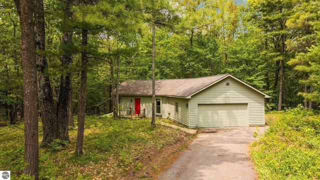1631 Melody Ln, Interlochen, MI 49643 - view of front facade featuring a garage, driveway, a view of trees, and a shingled roof