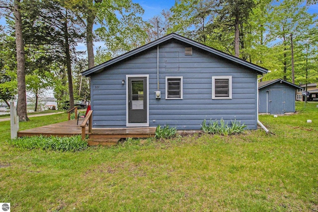 3131 Herron Rd, Frankfort, MI 49635 - rear view of house featuring a wooden deck, a yard, and an outdoor structure