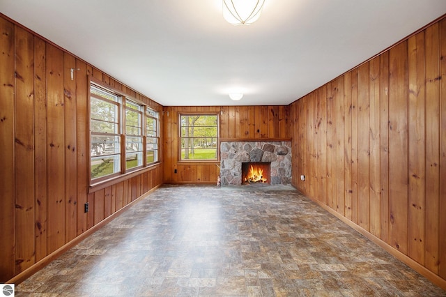3131 Herron Rd, Frankfort, MI 49635 - unfurnished living room featuring wooden walls, baseboards, stone finish floors, and a stone fireplace