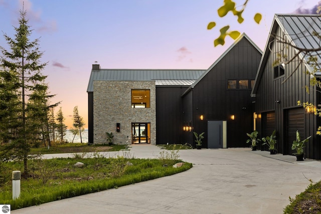 9371 Onominese Trl, Northport, MI 49670 - view of front of property with stone siding, a chimney, board and batten siding, a standing seam roof, and driveway